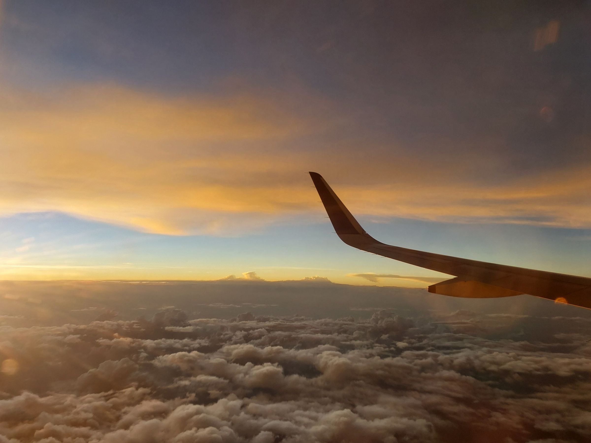 Aircraft wing over clouds at dusk